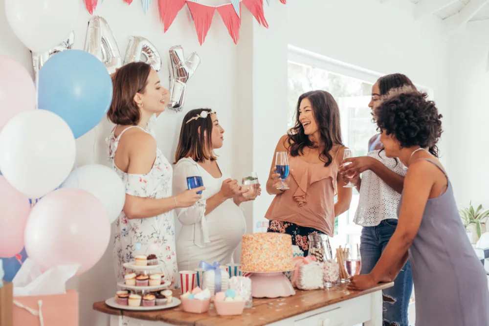 A table full of desserts for a baby shower with 5 people standing behind it.