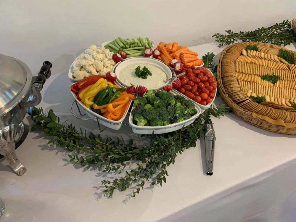 A table with a white table cloth and an assortment of cut vegetables neatly arranged on it.